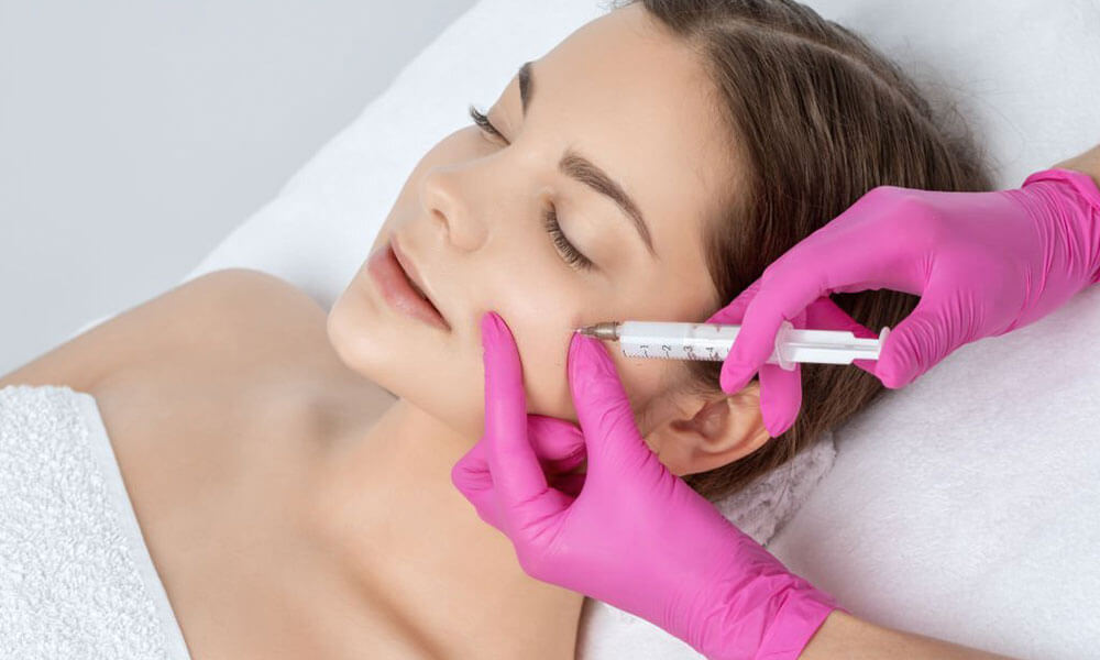 تصویر ارائه دهنده خدمات زیبایی که در حال تزریق چربی به صورت زن جوان است - تزریق چربی صورت